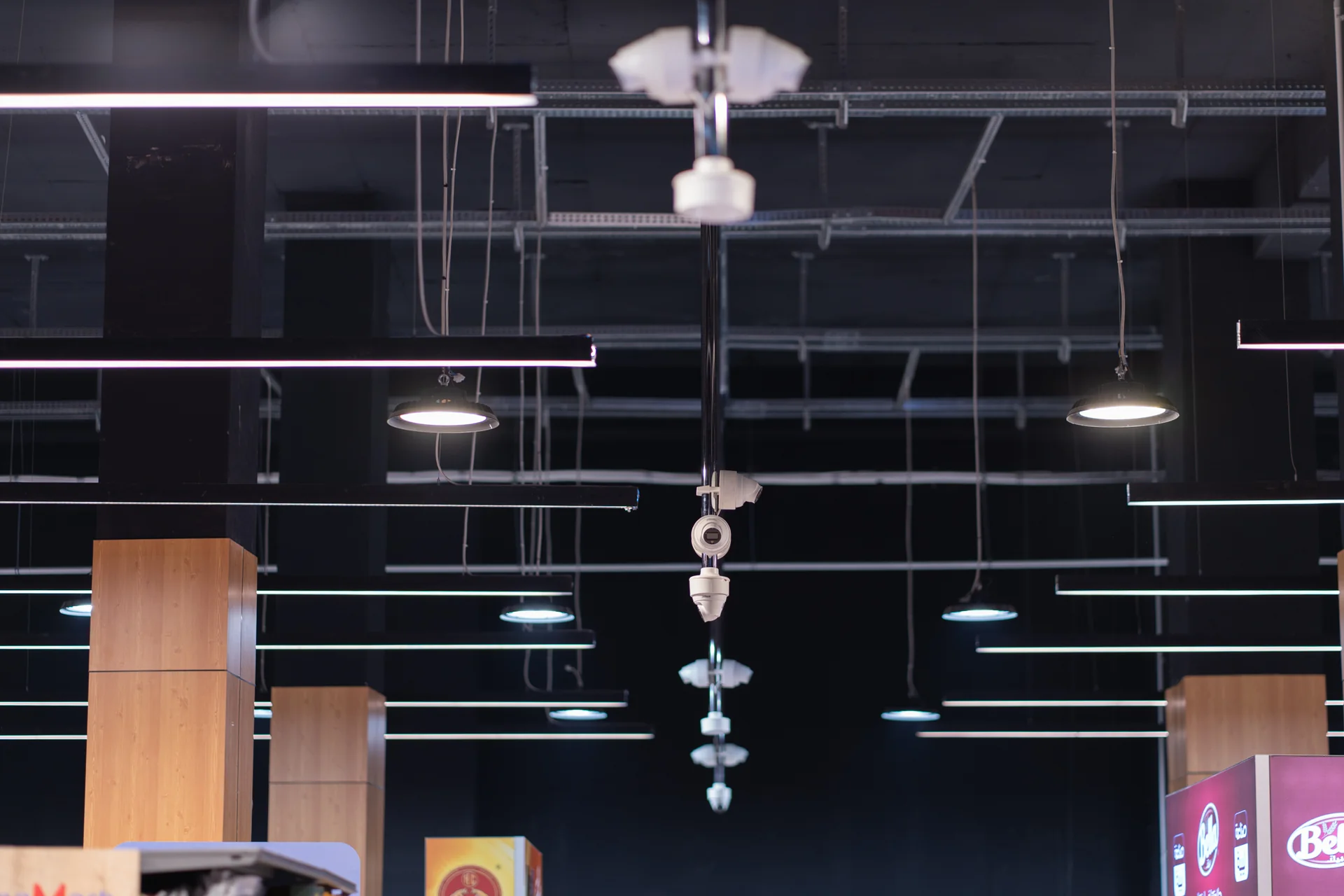The high ceiling over the sales floor: camera clusters suspended on long poles among the lighting and cable trays.