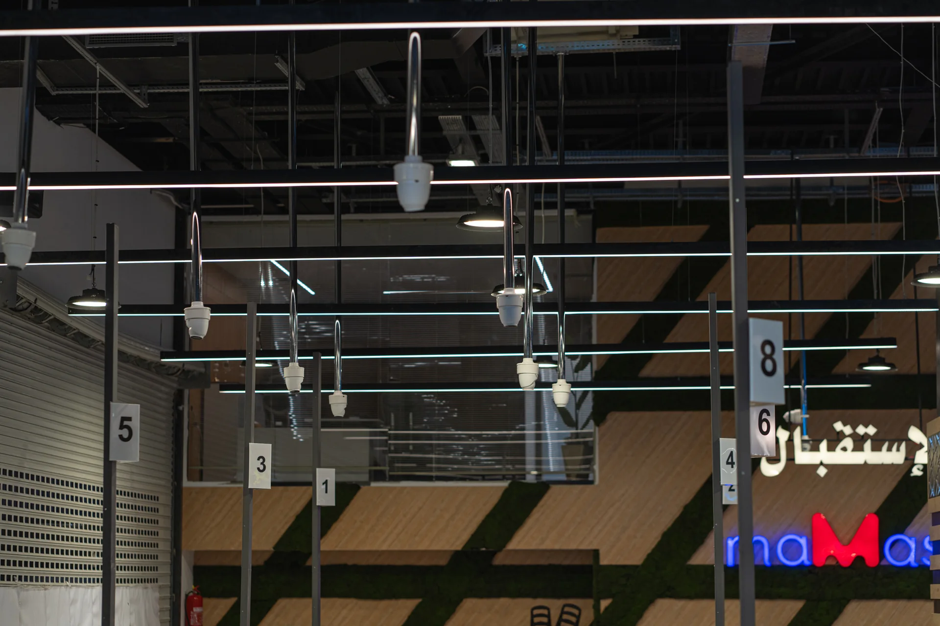 Mamash Supermarket entrance: suspended surveillance cameras on drop poles across the ceiling, above the reception area and the Mamash sign.