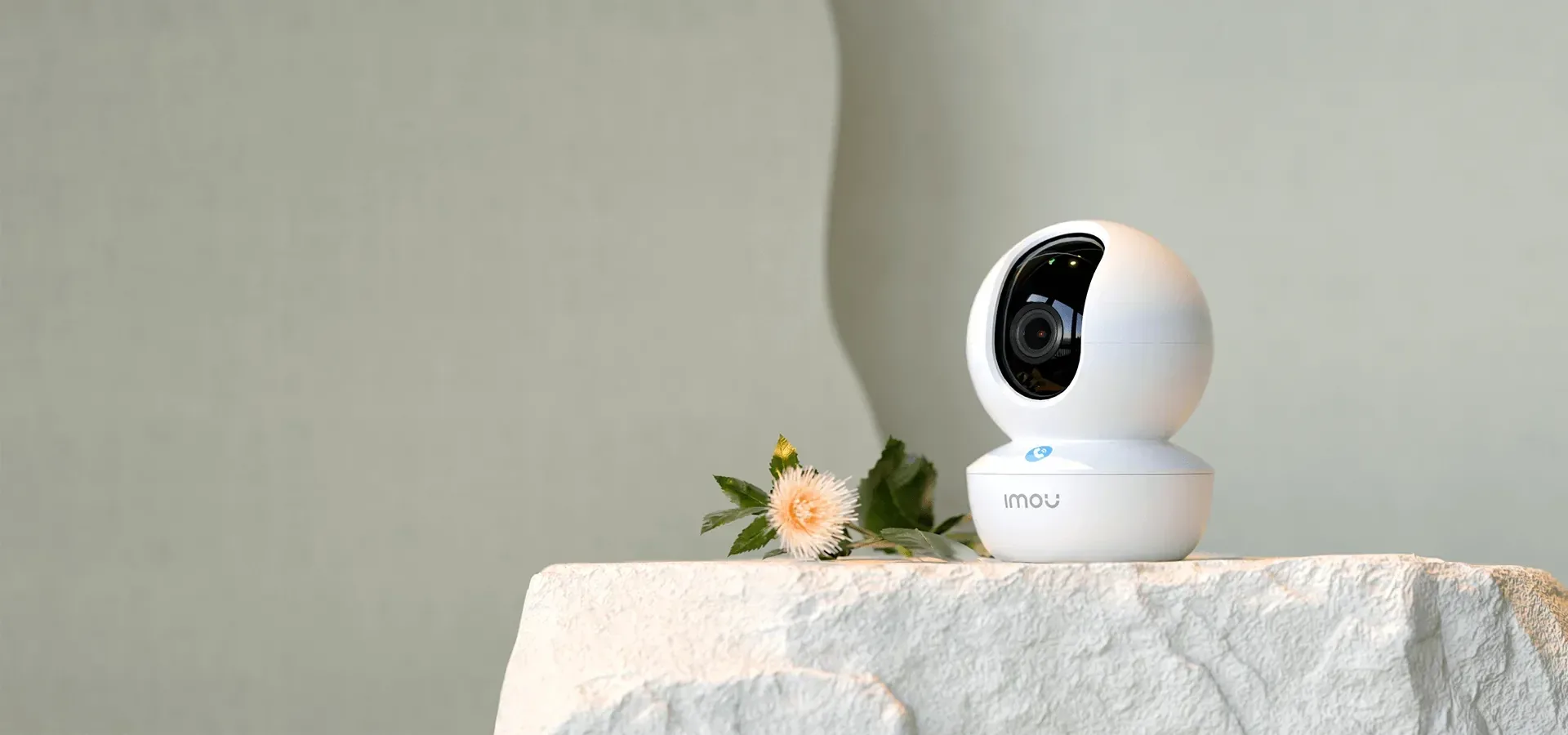 A white pan-tilt home camera on a stone plinth.