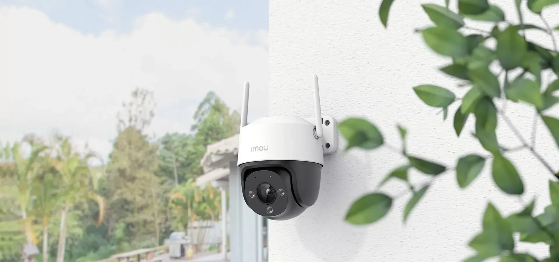 An outdoor pan-tilt camera mounted on a white wall.